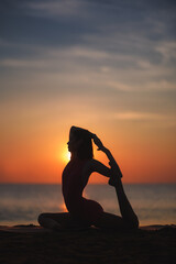 Silhouette of a Woman Doing Yoga on Beach at Sunrise