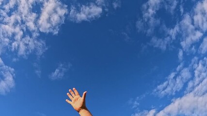 Raised human arm and hand enter from left, waving as a gesture, reach center, slide to right edge, then drop out while wispy clouds shift across deep blue sky, leaving copy space.