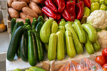 A pile of fresh vegetables: zucchini, peppers, cauliflower, potatoes on a market stall.

