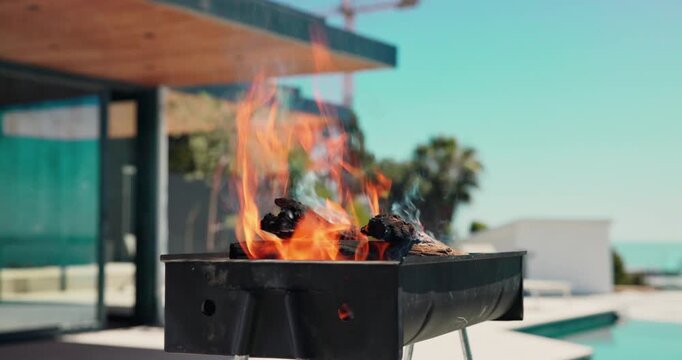 Empty, outdoor and bbq with flame in backyard for party, holiday and lunch on weekend by poolside. Cookout, barbecue and grill with fire, wood and heat for social gathering, celebration and vacation
