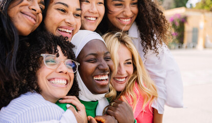 Fototapeta premium Diverse group of women having fun together outdoors. Multiracial girls laughing while hugging each other at city street. Female friendship concept