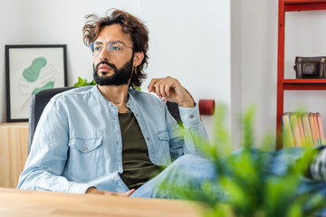 Portrait of young business man looking away while relaxing at home office workplace