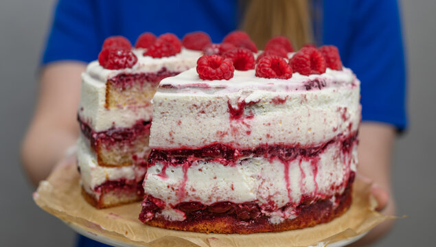 A light cake with whipped cream and raspberry jam, decorated with fresh summer seasonal fruits, raspberries, cake with raspberries
