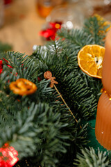 Macro shot of a tiny wooden gingerbread man decoration tucked into fresh fir branches alongside a dried orange slice for a Christmas centerpiece.