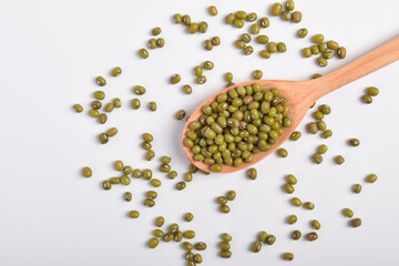 Mung beans with a wooden spoon on a white background.