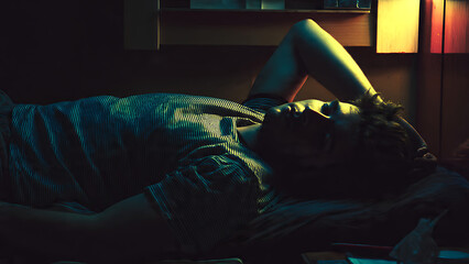 A person's reflective moment in a dimly lit room, experiencing a quiet struggle with thoughts