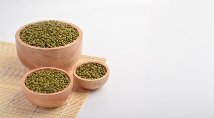 Mung beans in wooden bowls on bamboo mat background. Healthy plant based food concept with green...
