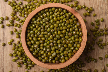 Raw mung beans in a wooden bowl on rustic wooden table, top view. Healthy organic legumes...