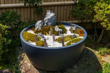 Fotobehang Zen Stenen Miniature japanese zen rock garden in round pot with moss stones and white gravel creating calm meditative outdoor scene  © gyana08