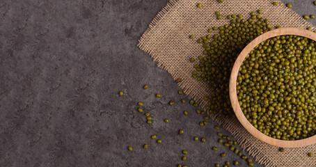 Mung beans in wooden bowl on dark stone background, top view. Healthy plant based food concept with...