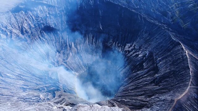 The crater of the volcano on Mount Bromo is located inside the Tengger caldera. Sulfurous fumes rise into the air on the island of Java, an active volcano in Indonesia, as seen from a bird's-eye view.