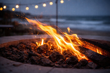 Outdoor Fire Pit Flames And Sparks By The Sea At Dusk With String Lights
