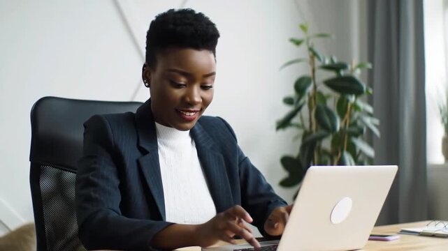 Smiling businesswoman working on laptop in office, background of plant and window, for work or presentation