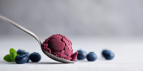 Spoon holding a scoop of delicious berry ice cream with fresh blueberries and mint, a refreshing summer dessert