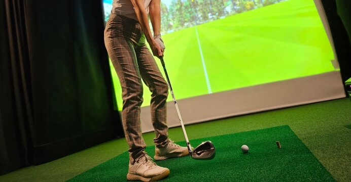 Professional female golfer holding club playing golf indoors on golf simulator concept