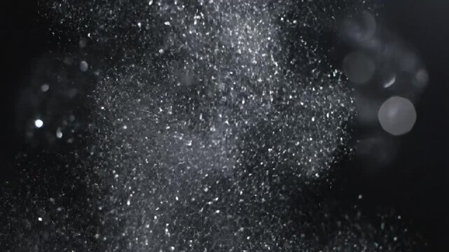 Bright, shimmering dust motes suspended in air against a deep, dark, abstract background
