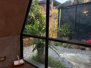 Jiufen Sunroom Corner: Sunroom corner featuring floor-to-ceiling glass panels, a low wooden sitting desk, and panoramic views of the remote mountainous landscape in Jiufen.