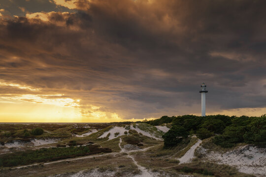 view of the sand dunes and lighthouse of Dueodde on the Danish island of Bornholm in warm evening light