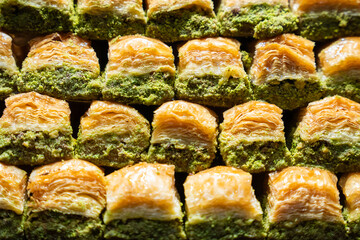 Extreme close-up of Turkish baklava with pistachios, showing flaky pastry layers and chopped nuts. Traditional dessert detail.

