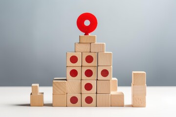 Obraz premium Wooden cubes pyramid with red dots and location pin on top symbolizing growth, achievement and business success