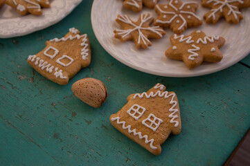 Painted traditional Christmas gingerbreads arranged on white plates on old vintage painted table, various xmas shapes
