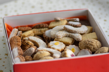 Various traditional Christmas sandbakelse, gingerbread and vanillekipferl arranged in white and red box on stars tablecloth