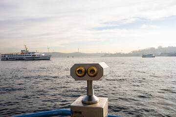 Close-up view of tourist binoculars on the Galata Bridge in Istanbul, overlooking the Golden Horn. Public viewing scopes for observing the waterfront cityscape.


