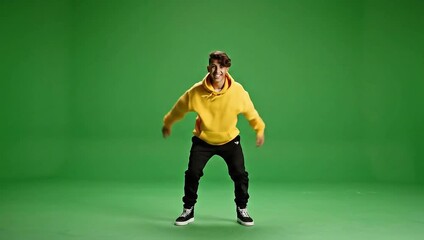 Young man dancing energetically in a studio with a green screen background - Powered by Adobe