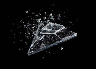 scattered shards of broken glass, triangular main piece with small fragments flying, dark background, high speed photography capturing explosion, concept of destruction and disintegration