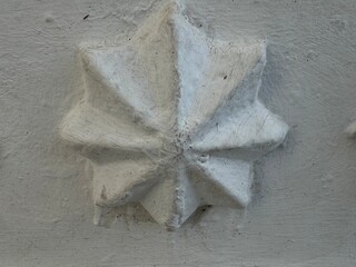 Textured white plaster relief with radial design on a rough wall surface for background use