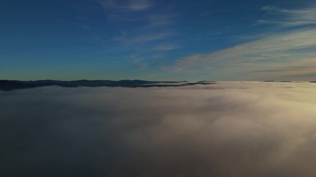 Sun above a sea of fog and clouds with mountain ridge under blue sky aerial view of foggy mountains