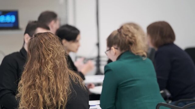 Group of professionals in meeting room discuss notes and ideas at round table