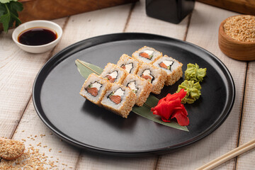 Sesame coated sushi rolls with fresh salmon and cream cheese served on a black plate with ginger © Hihitetlin
