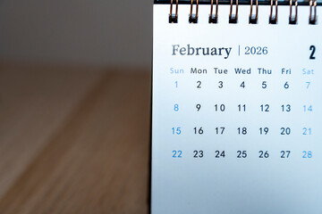 Close-up of a calendar for February 2026, displaying dates on a spiral-bound format, representing time management, planning, and organization in a minimalistic setting.