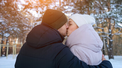 Fervent Couple Shares Warmth In Cold Scenery, Tender Couple Kisses Amidst Snow With Bright Sun Flares, Intimate Moment Captured As Lovers Embrace In Winter Snow Under Gentle Sunlight
