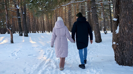 Couple Walking In Snowy Pine Forest, Hand In Hand Along Narrow Trail With Tall Trees And Crisp Footprints, Relaxed Pace And Soft Light Create Calm Outdoor Romantic Stroll Atmosphere