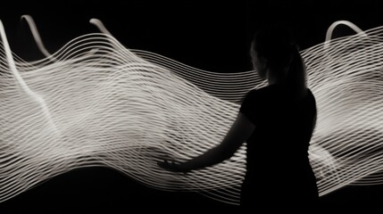 Silhouette of Woman Interacting with Glowing Light Trails, Abstract Long Exposure Light Painting on Black Background, Concept of Digital Future Connectivity Energy or Data Flow