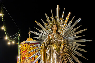 Religious Virgin Mary Statue With Radiant Halo at Night Festival Parade Under Warm Lights