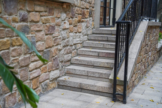 Black wrought iron railing near staircase on tile porch of private home.