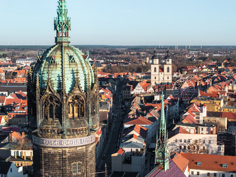 Close telephoto aerial view from the tower of All Saints&rsquo; Church in Wittenberg toward the market square and St. Mary&rsquo;s Church, with a Christmas market featuring a Ferris wheel.
