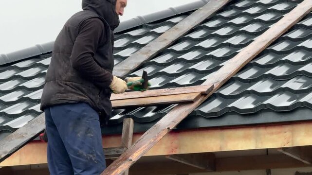 A master stove setter makes a ladder to the roof of a house. For the construction of a heating stove chimney. Close-up.