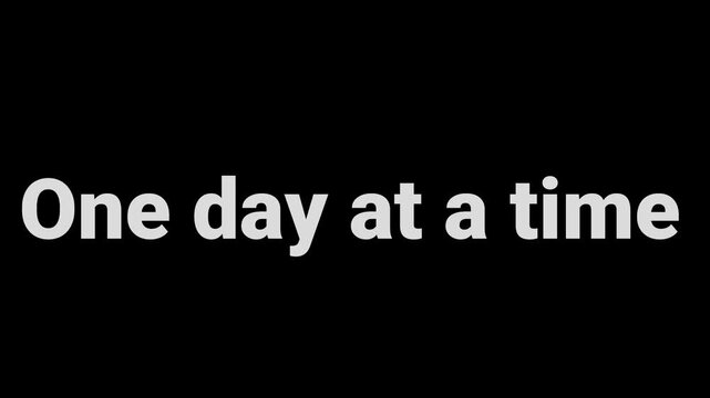 Inspiring distressed white text quote one day at a time centered on a black background for motivation