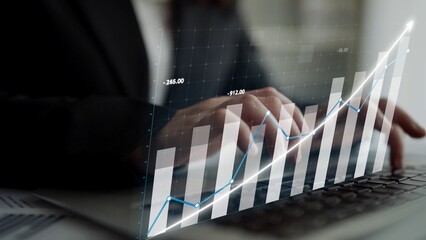 A business professional engages with digital graphs on a laptop, illustrating financial data analysis and trend growth in a modern office environment. Copula