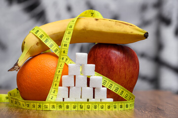 Fresh fruit, banana, apple and orange on the background of the sugar pyramid, diabetes, white...