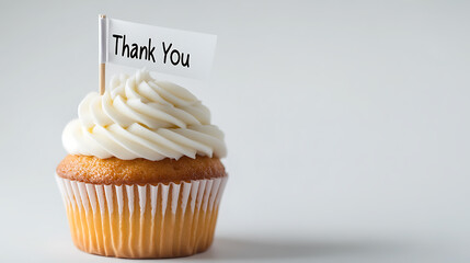 A golden cupcake topped with creamy white frosting, adorned with a small flag that reads "Thank You", conveys gratitude and sweetness in a simple, yet elegant dessert.