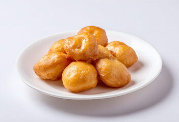 Golden fried dough balls served on a white plate isolated on a clean studio background