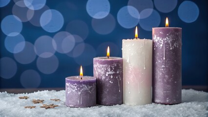 Lit purple and white candles burning on snowy surface with blue bokeh lights in serene winter holiday atmosphere
