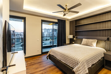 Luxurious Modern Bedroom with Gray Tones, Wood Flooring, a Quilted Bedspread, and Recessed Lighting
