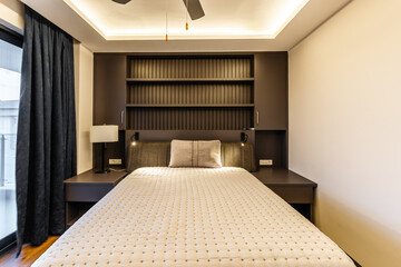 Contemporary Dark-Themed Bedroom Featuring Built-in Fluted Wall Panel Shelving and Access to a Private Balcony