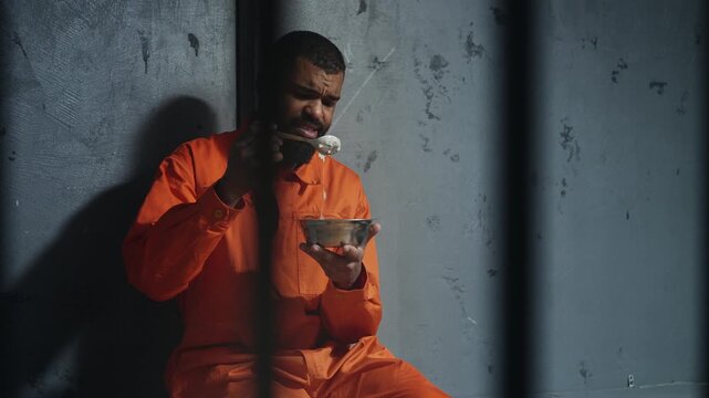 Young African American male inmate disgusted while eating bland prison food